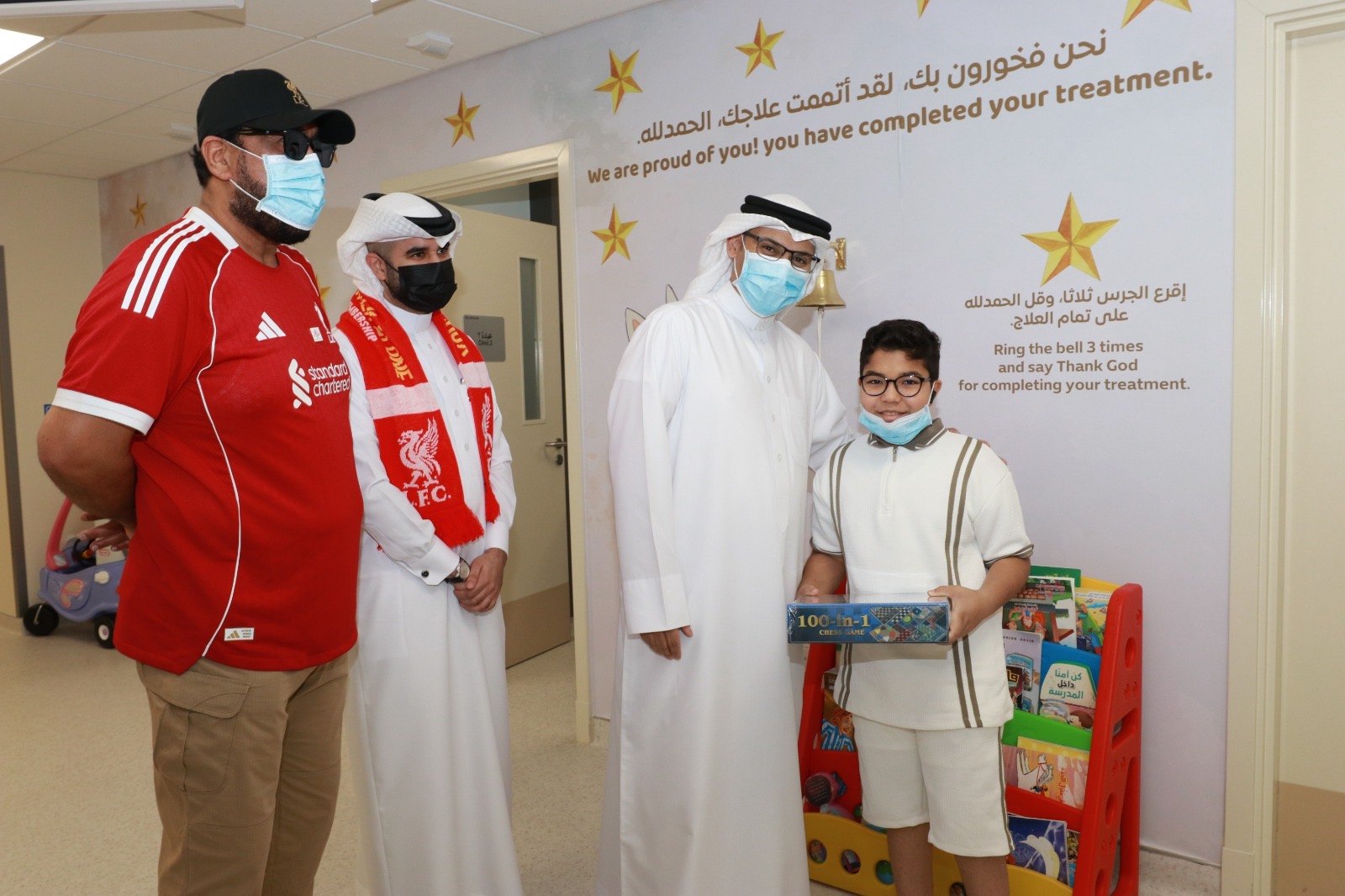 OLSC Bahrain representatives with a young person holding a boxed game.