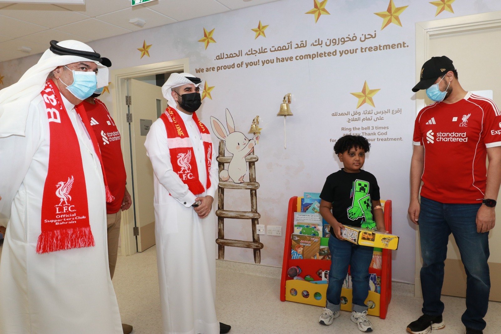 OLSC Bahrain representatives with a child holding a boxed gift.